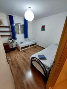 een slaapkamer met een bed en een raam met blauwe gordijnen bij מצפה 1050 in Neve Ativ
