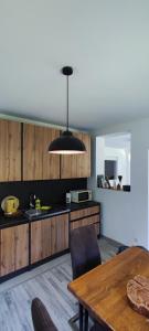 a kitchen with a table and a black light fixture at Anur Apartment in Bihać