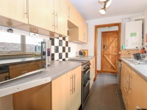a kitchen with wooden cabinets and stainless steel appliances at Seashell Cottage in Lowestoft