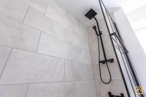 a shower with a shower head in a bathroom at Cosy 5 bedroom house - Central By Valore Property Services in Loughton