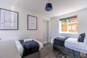 LoughtonにあるCosy 5 bedroom house - Central By Valore Property Servicesのベッド2台と窓のある寝室