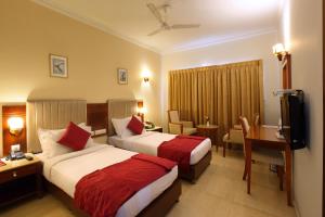 a hotel room with two beds and a desk at Cochin Palace in Cochin