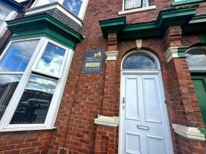 a brick building with a white door and windows at A&A Luxury Stay Bettys in Pallion