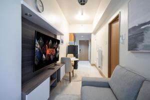een woonkamer met een bank en een tv aan de muur bij Shore 3 Residences, Mall of Asia Complex in Manilla