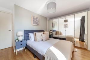 a bedroom with a large bed with a blue headboard at The South Wimbledon Collection in London