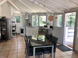 uma cozinha com mesa e cadeiras num quarto em La petite maison au chêne em Belin-Beliet