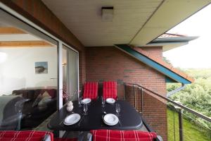 a black table with red chairs on a balcony at LM7-15 - Ferienwohnung Typ AB in Schottwarden