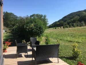 3 Stühle und ein Tisch auf einer Holzterrasse in der Unterkunft Gîte La Glycine in Dun