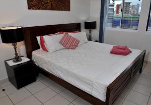 1 dormitorio con 1 cama grande con almohadas rojas y blancas en Inner city Cardona Court apartment, en Darwin