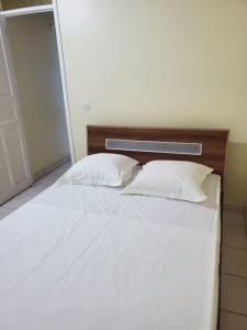 Una cama con sábanas blancas y almohadas en un dormitorio en petit paradis du thermaliste, en Lamentin
