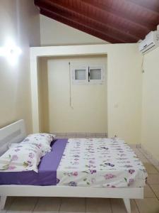 1 dormitorio con 1 cama con edredón morado y blanco en petit paradis du thermaliste, en Lamentin