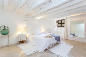 a white bedroom with a bed and a mirror at Son Rullan in Deia