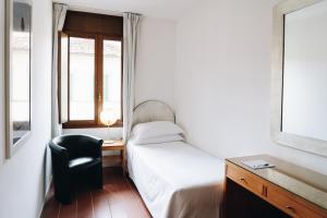 a bedroom with a bed and a chair and a desk at Hotel Palazzo Ognissanti in Florence