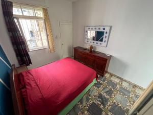 een kleine slaapkamer met een rood bed en een raam bij Milingona City Center Hostel in Tirana