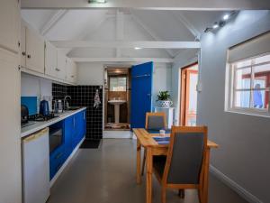 Una cocina con gabinetes azules y una mesa de madera. en Gifted Garden Cottage, en Swellendam