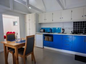 Una cocina con gabinetes azules y una mesa de madera. en Gifted Garden Cottage, en Swellendam 16 fotos más