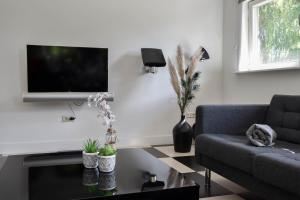sala de estar con sofá y TV en la pared en Villa Vera, en Zeewolde