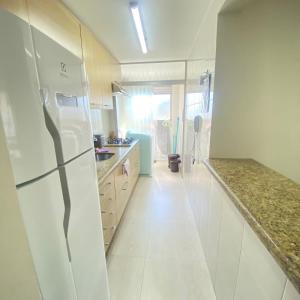 a kitchen with a white refrigerator and white tile floors at Jardim Botânico Curitiba in Curitiba