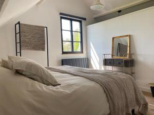 a white bedroom with a bed and a mirror at Vakantiehuis Zand7 in Lommel