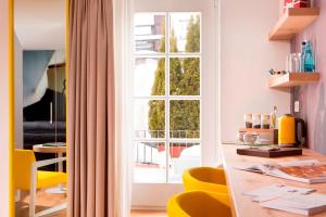 Zimmer mit einem Tisch mit gelben Stühlen und einem Fenster in der Unterkunft Small Luxury Hotel Goldgasse in Salzburg