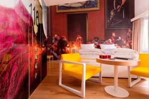 Zimmer mit gelben Stühlen, einem Tisch und einem Gemälde in der Unterkunft Small Luxury Hotel Goldgasse in Salzburg
