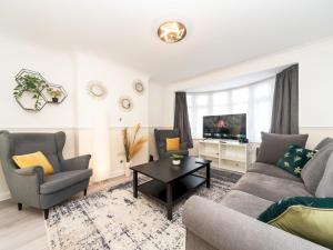 a living room with a couch and chairs and a tv at Pass the Keys Spacious 4 Bed House Free Parking Near Station in Bexleyheath