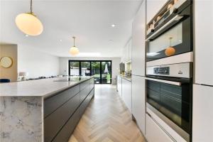 uma cozinha com armários brancos e uma grande ilha de cozinha em Modern 3 bed Entire House, Gym & Underfloor Heating em Hersham