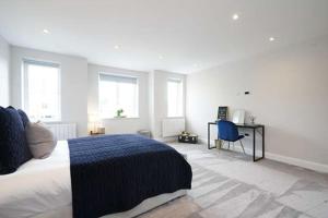 a bedroom with a bed and a desk and windows at Modern 3 bed Entire House, Gym & Underfloor Heating in Hersham