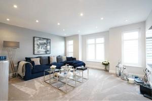 a living room with a blue couch and a table at Modern 3 bed Entire House, Gym & Underfloor Heating in Hersham