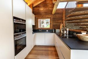a kitchen with white cabinets and a wooden wall at Sonnhalde II - Luxury Chalet in Saas-Fee