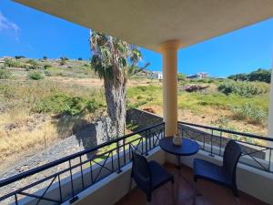 a balcony with a table and chairs and a palm tree at Ocean Gardens in Caniço +7 photos