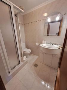 Un baño con lavabo, inodoro y espejo. en Ocean Gardens, en Caniço