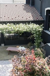 Bucolico Monza في مونزا: حديقة بها زهور بيضاء ومقعد على مبنى