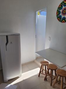 a kitchen with a table and two stools and a refrigerator at Kitchenette Charmosa no Itagua in Ubatuba