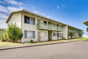 a white building with green balconies on a street at Walk to Downtown Hilo Condo with Pool Access! in Hilo