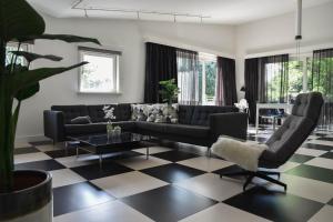 sala de estar con sofá negro y suelo a cuadros en Villa Vera en Zeewolde