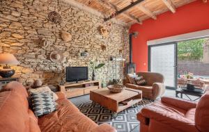 a living room with couches and a stone wall at Au Paradis des 2 Petites Abeilles in Félines-Minervois