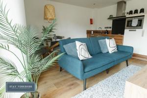 a blue couch in a living room with a plant at Stay Yorkshire City Centre Apartments in Sheffield