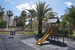 a playground with a slide in a park with palm trees at Estrella del Mar II in Denia