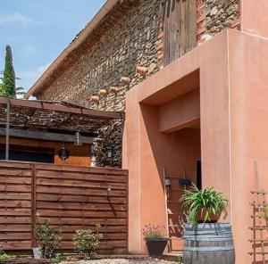 a house with a wooden fence and a building at Au Paradis des 2 Petites Abeilles in Félines-Minervois
