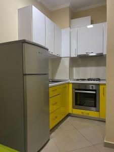 a kitchen with yellow and white cabinets and a refrigerator at Hotel Adria in Shëngjin