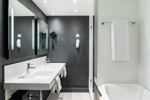 a white bathroom with two sinks and a bath tub at AC Hotel by Marriott Nice in Nice