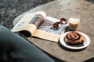 a book and a cup of coffee and a pastry on a table at Go Hotel Østerport in Copenhagen