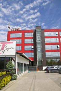 a red building with a car parked in front of it at Hotel City Ploiesti in Ploieşti