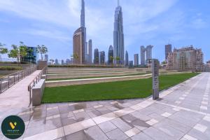 a park with benches and grass in front of a city at Vogue Downtown Views ll - Burj Khalifa View near Dubai Mall in Dubai