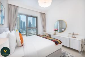 a white bedroom with a large window at Vogue Downtown Views ll - Burj Khalifa View near Dubai Mall in Dubai