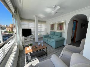 uma sala de estar com um sofá azul e uma televisão em Apartamento a un minuto de la playa de Levante em Benidorm