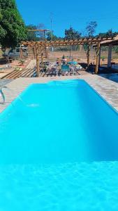 einen großen blauen Pool neben einer Terrasse in der Unterkunft Chácara do Cardoso in Três Marias