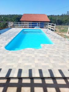 uma grande piscina azul num pátio de azulejos em Chácara do Cardoso em Três Marias