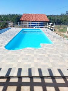 a large blue swimming pool on a tile patio at Chácara do Cardoso in Três Marias +14 photos